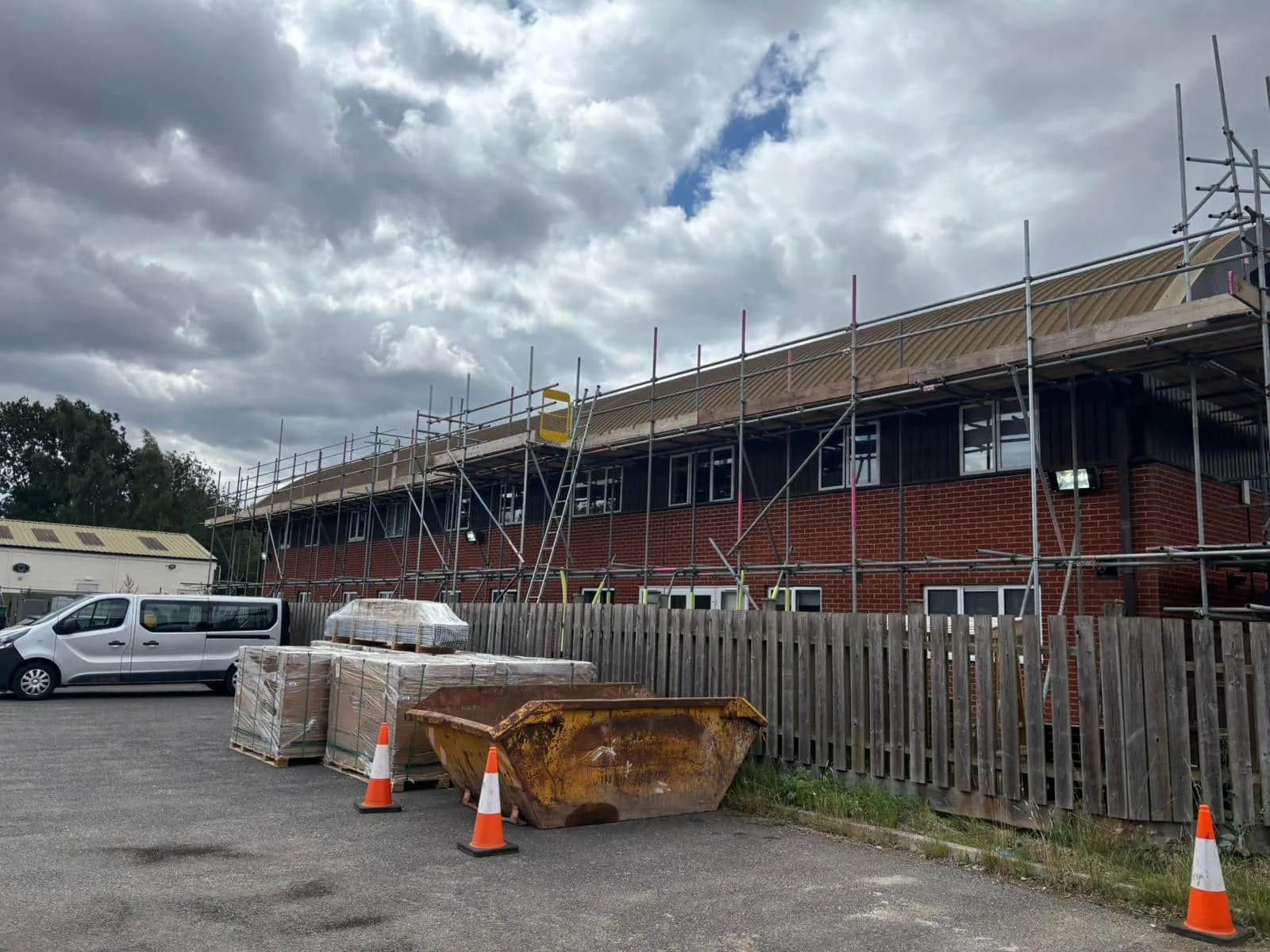 Solar panel scaffold across main school building with skip and materials on site