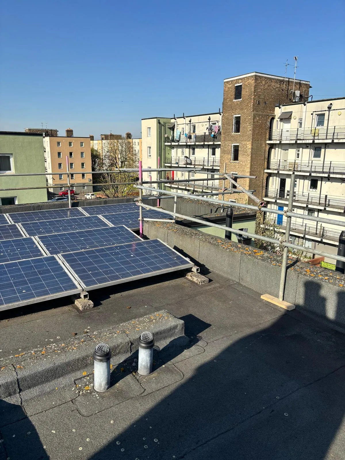 Solar panels on flat roof with perimeter edge protection scaffold, Blaker Court Blackheath
