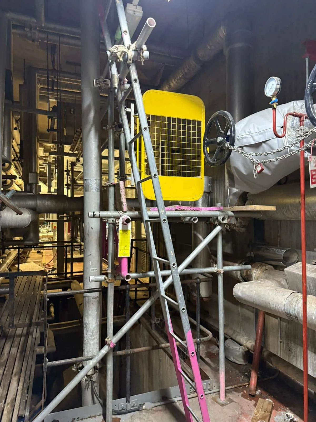 Internal scaffold in live plant room with pipework and machinery, Martin-Baker