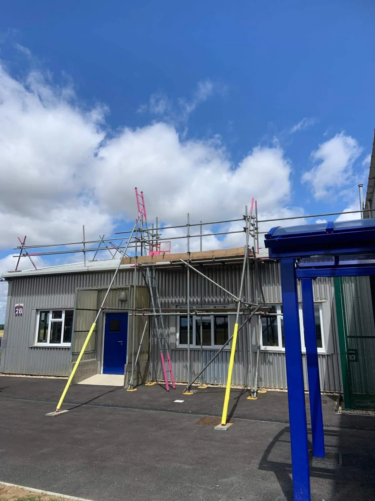 Roof access scaffold on hangar building for solar installation, Martin-Baker Denham
