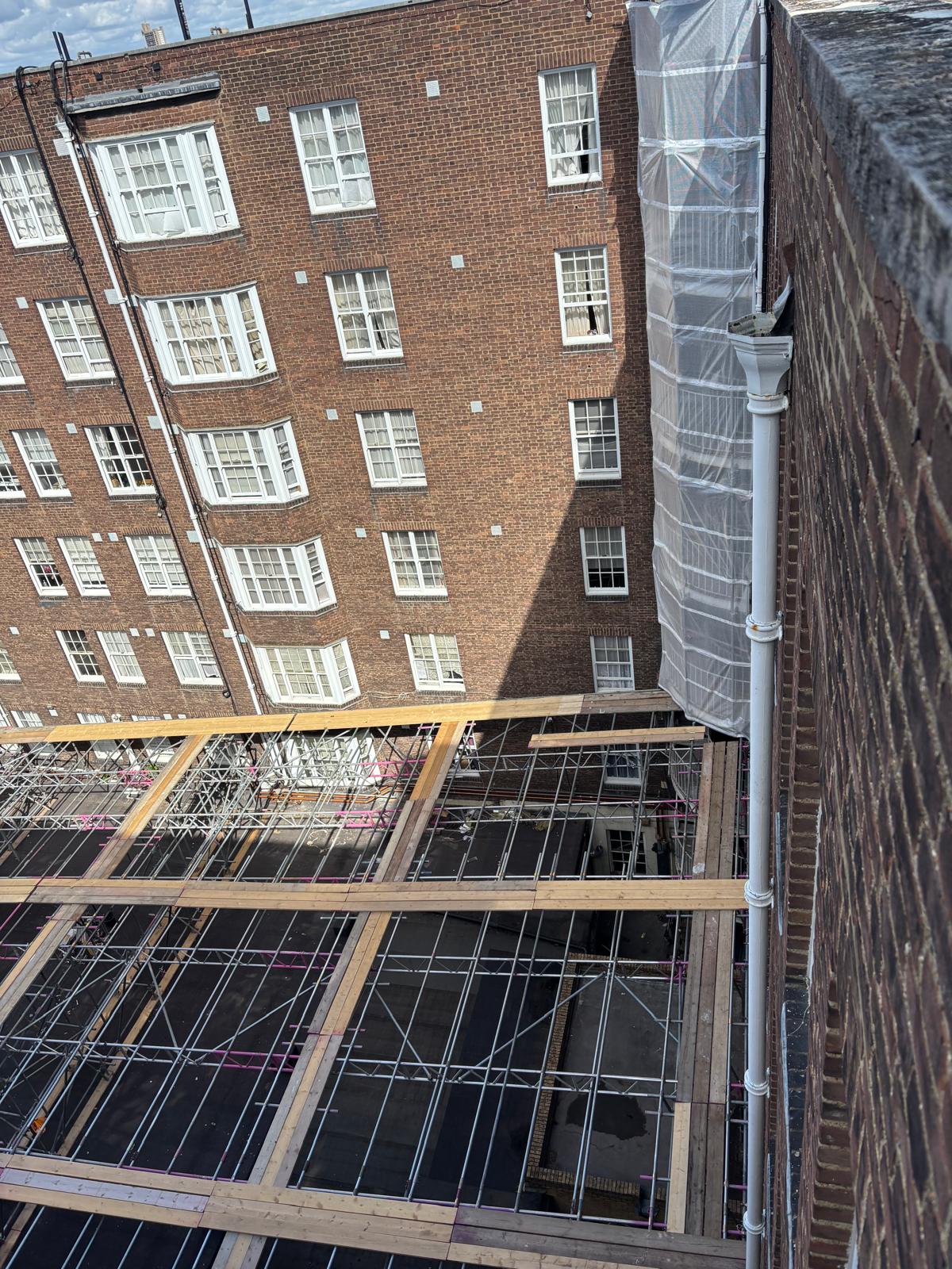 Scaffold beams landing on the elevation and bolted into the building at Queensway Market, London W2 - Pinnacle Scaffolding
