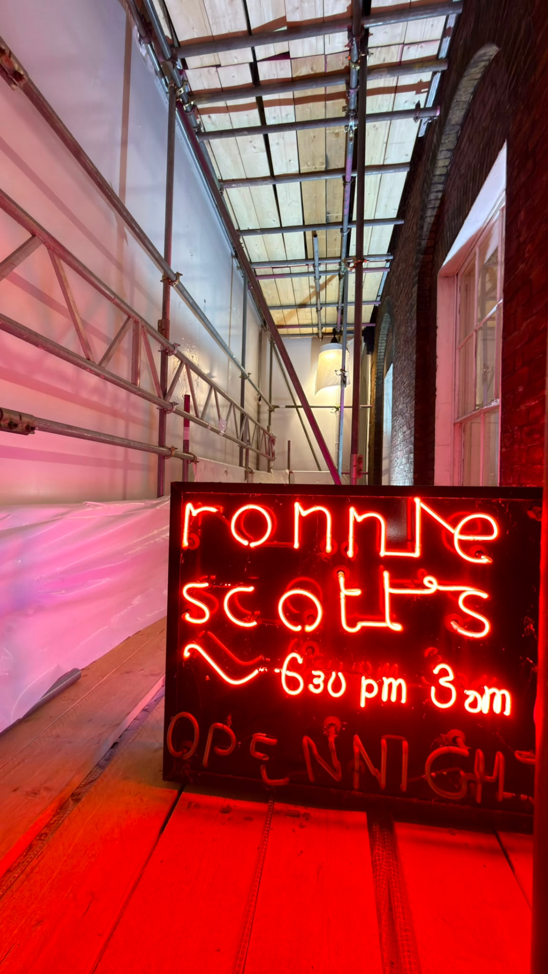 Inside the encapsulated scaffold at Ronnie Scott's, Soho, with the club's neon signage kept clear and visible - Pinnacle Scaffolding