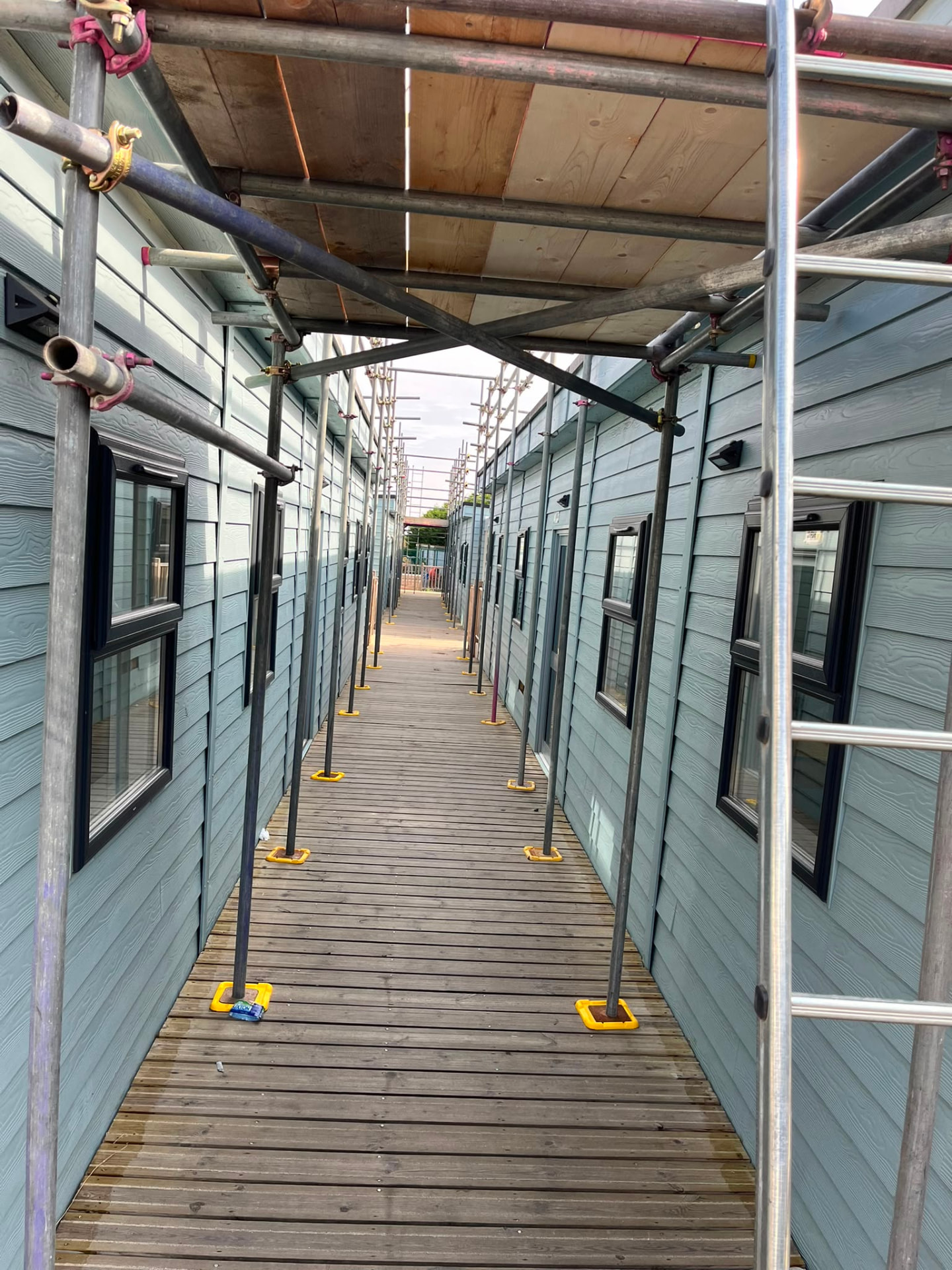 Covered walkway with boarded roof keeping the route through the site open during solar panel scaffold works in Bromley - Pinnacle Scaffolding