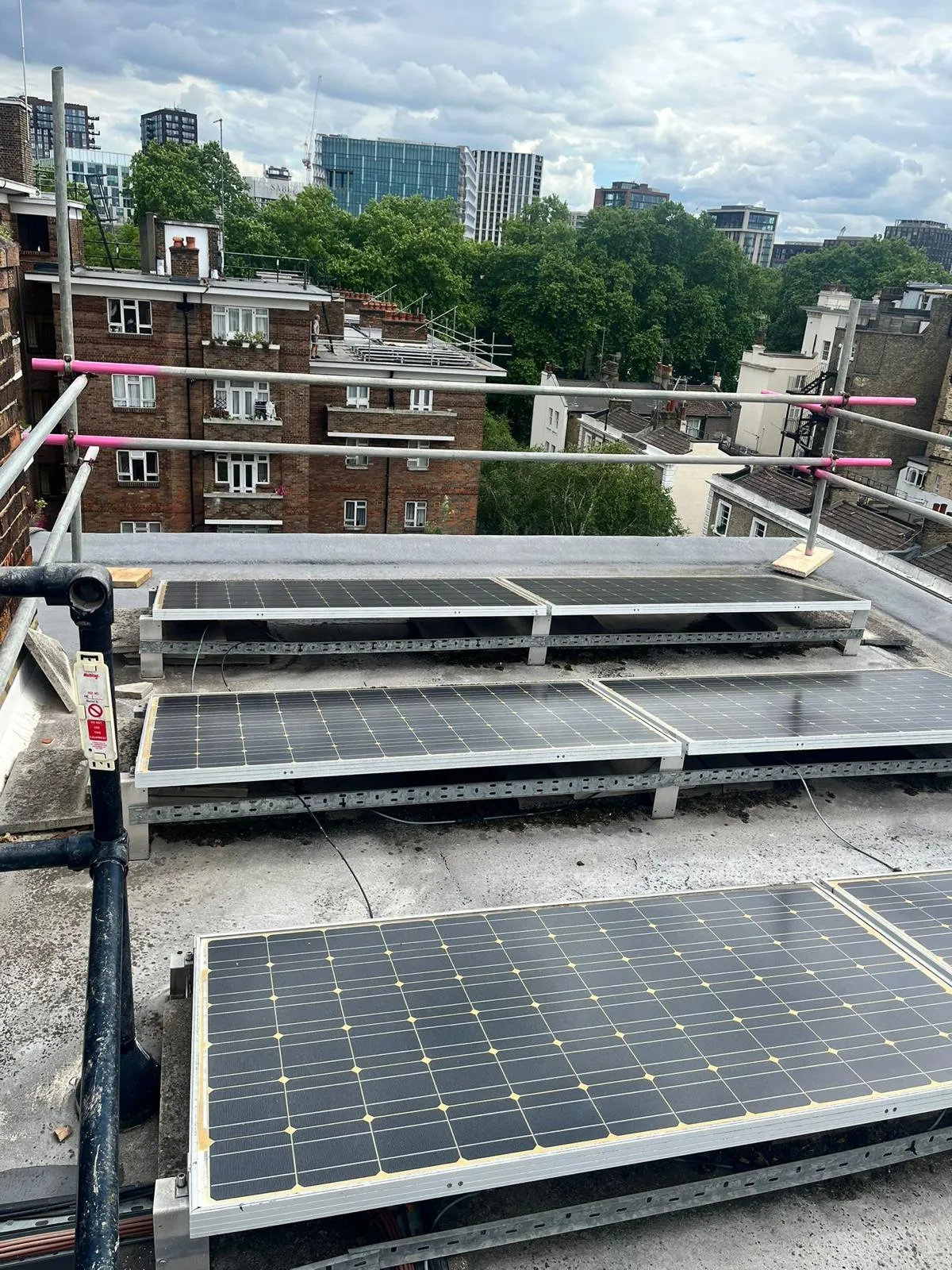 Solar panels on flat roof with edge protection scaffold, central London