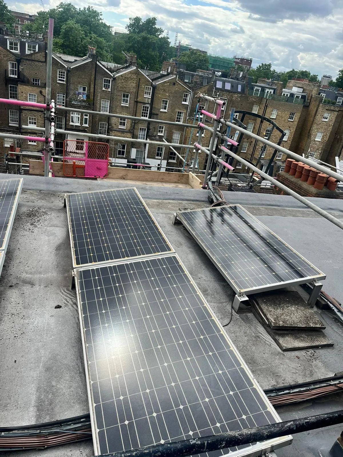 Solar panel installation with scaffold edge protection on residential block roof